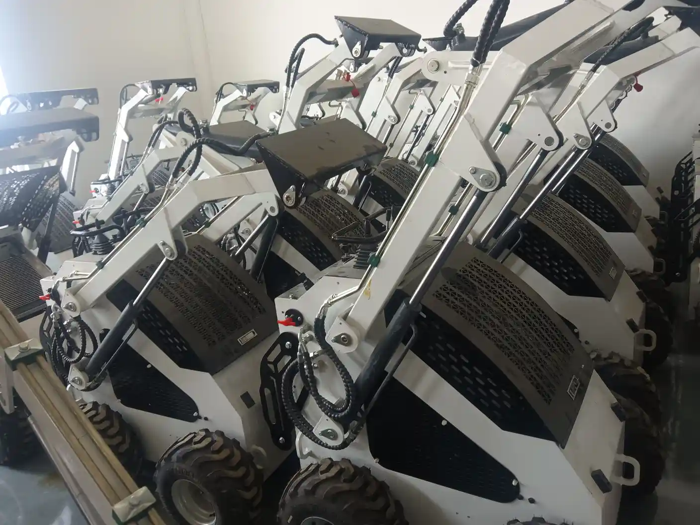 White skid steer loader boom assemblies arranged in the production workshop