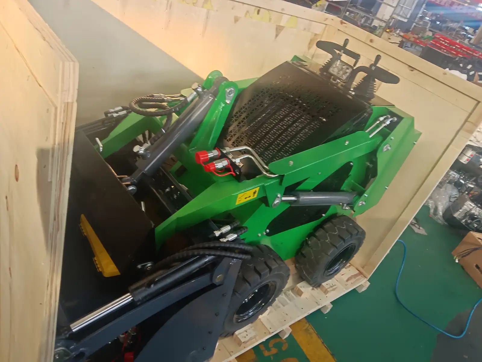 Green skid steer loader secured inside a wooden shipping crate